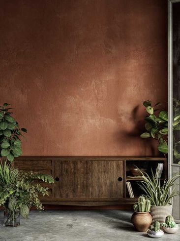 Interieur in Terrakotta-Orange mit Pflanzen, Kommode, Stuckwand und Dekor.